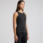 Woman in a black sleeveless top and black jeans standing against a plain background.