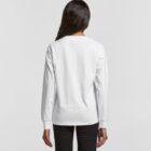 Woman in a white long-sleeve shirt and black pants, shown from behind against a plain background.