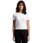 Woman with dark curly hair wearing a white t-shirt and black pants, standing against white background.