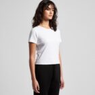 Woman in a white t-shirt and black pants standing against a plain gray background.