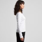 Woman in a white long-sleeve shirt and black pants standing in profile against a plain background.