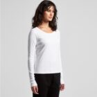 Woman in a white long-sleeve shirt and black pants standing against a plain background.