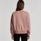 Person with long hair wearing a mauve sweatshirt and black pants, seen from the back.