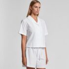 Woman in a white button-up shirt and shorts against a plain background.