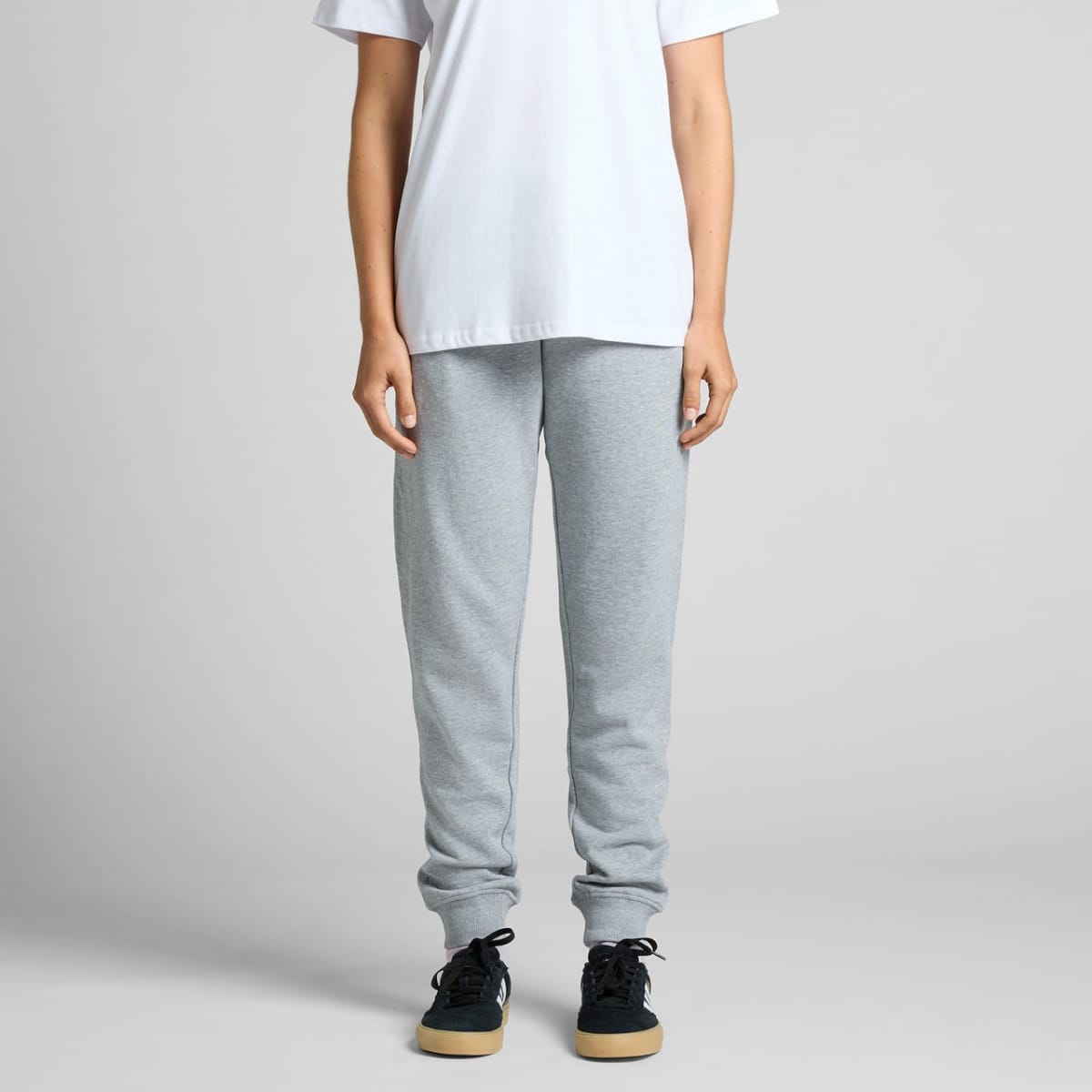 Person in a white t-shirt and gray sweatpants standing against a plain background.