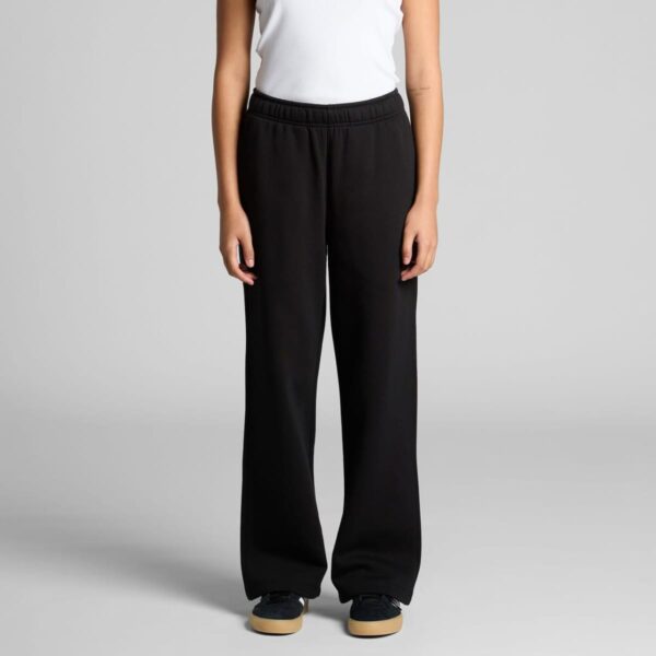 Person wearing a white top and black wide-leg pants, standing against a gray background.