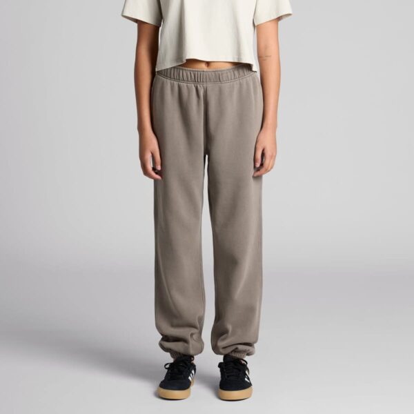 Person in a cream shirt and gray sweatpants, wearing black sneakers, standing on a plain background.