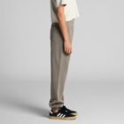 Person wearing a beige crop top, gray joggers, and black sneakers with white stripes.