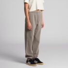 Person in beige crop top, gray sweatpants, and black sneakers on a plain background.