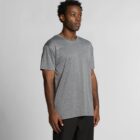 Man in a gray short-sleeve t-shirt and black pants standing against a plain background.