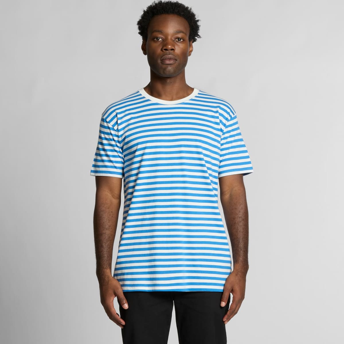 Man wearing a blue and white striped T-shirt, standing against a plain background.