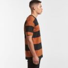 Man in a black and brown striped t-shirt standing in profile against a plain background.