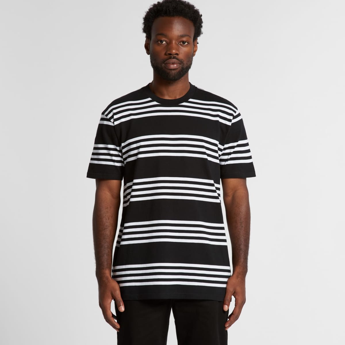 Man wearing a black t-shirt with white horizontal stripes, standing against a plain background.