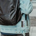 Person in a denim jacket with a black backpack and a hanging keychain.