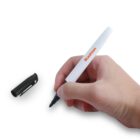 Hand holding a white marker next to its black cap on a white background.