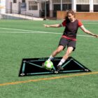 Soccer player practicing on field with training mat and ball.