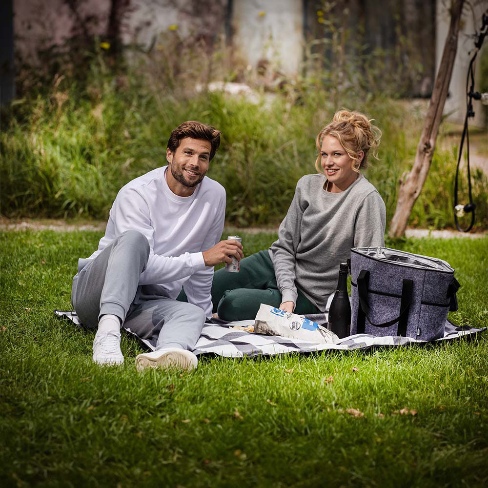 A male and female couple sitting on a picnic blanket on grass