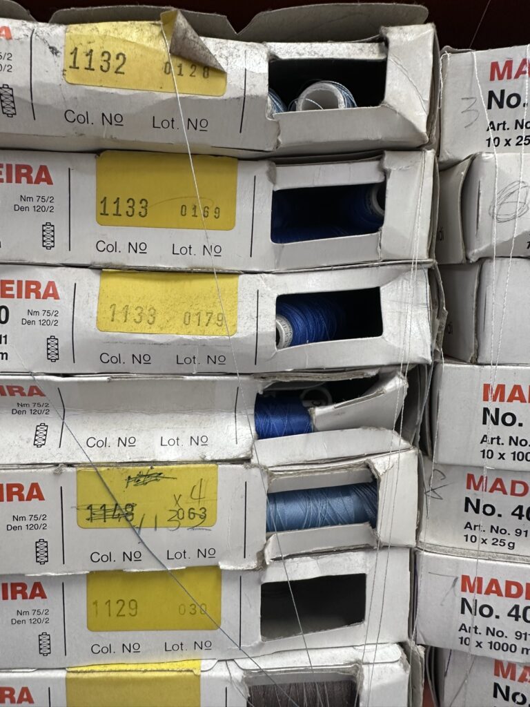 Behind the scenes: Boxes of blue sewing thread spools for embroider logos in Australia.