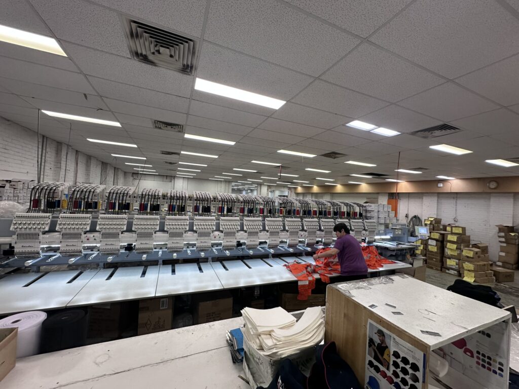 Behind the scenes in Australia, a person operates a machine to embroider logos in a factory.
