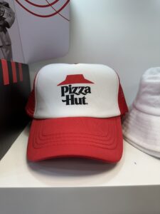 Red and white Pizza Hut cap featured in the FAQ section display.