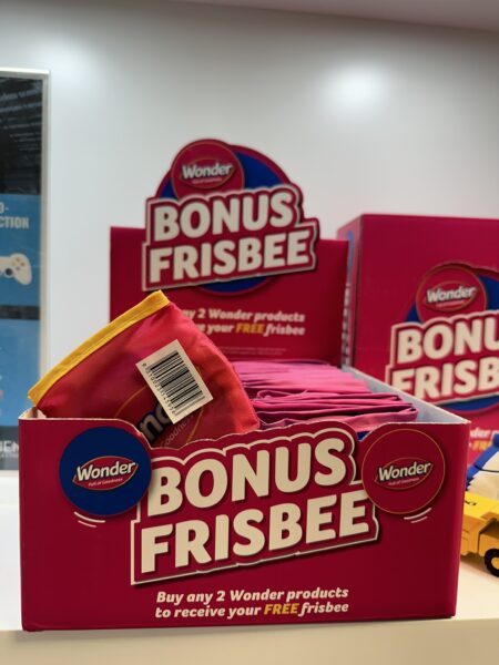 Display box of Wonder Bread custom merch frisbees with bold text promoting a free frisbee offer.