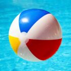 Colorful beach ball floating on clear blue pool water.