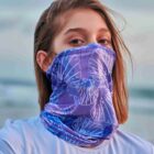 Person wearing a purple butterfly-patterned neck gaiter and a light blue shirt.