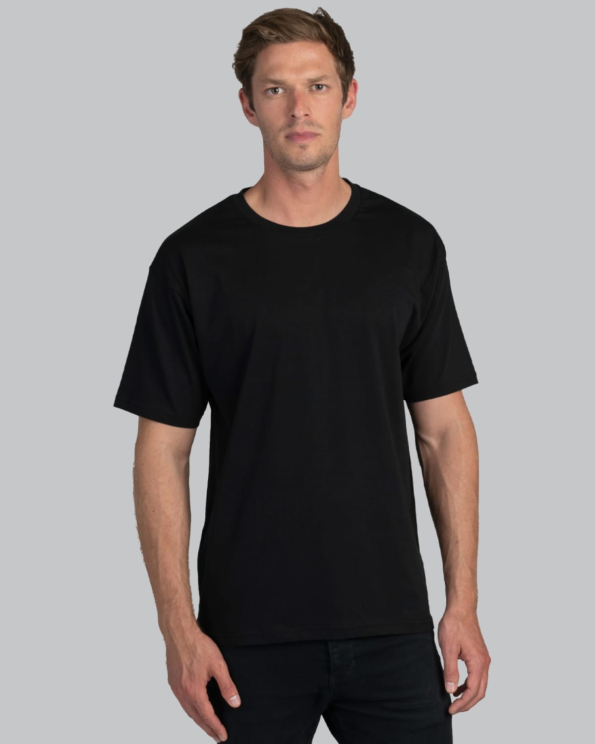 Man wearing a plain black t-shirt and black pants, standing against a gray background.