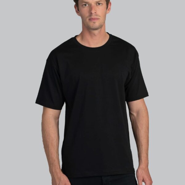 Man wearing a plain black t-shirt and black pants stands against a plain gray background.