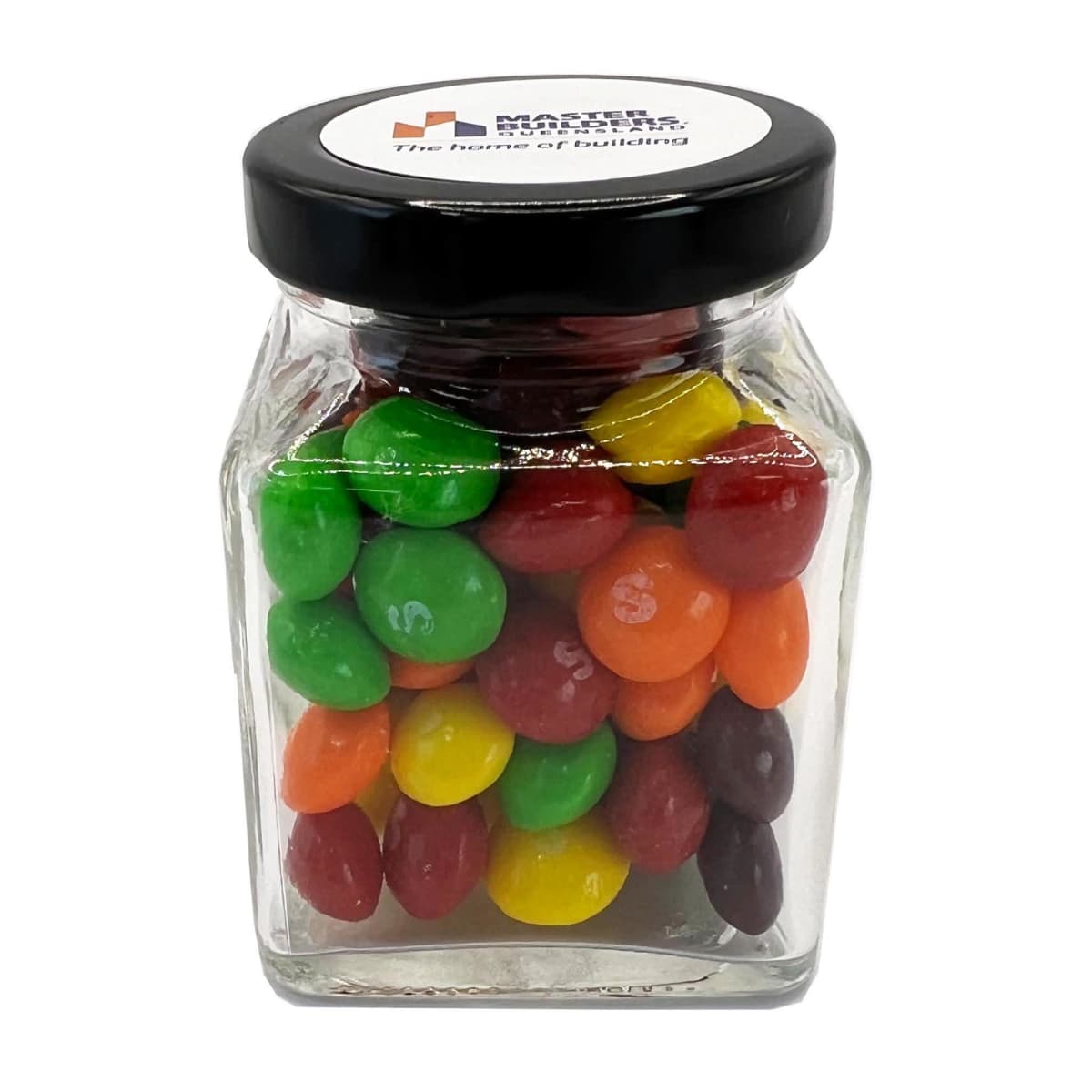 A clear jar filled with colorful candy coated sweets and sealed with a black lid.