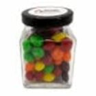 A glass jar filled with colorful candy pieces and a black lid.