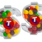 Two clear, dollar sign-shaped containers filled with colorful candies.