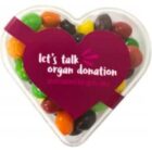 Heart-shaped box of colorful candies with lets talk organ donation on the lid.