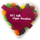 Heart-shaped container with colorful candies, labeled lets talk organ donation.