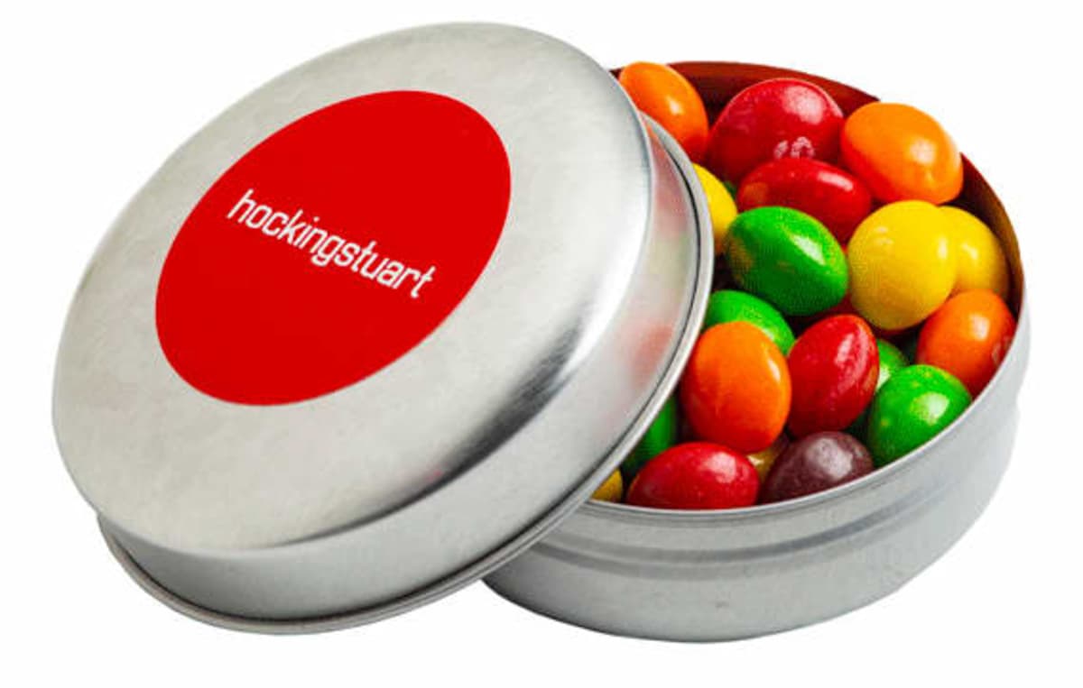 A metal tin of colorful candy with a red label reading hockingstuart on the lid.