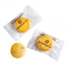 Three round cookies, two in clear packaging labeled MODORAS, one unwrapped, on white background.