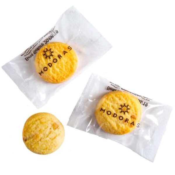Three round cookies, two in clear MODORAS packaging, one unwrapped, on a white background.