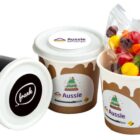 Three branded paper cups, one filled with colorful candy in a clear bag.