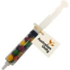 A syringe filled with colorful candy, labeled Australian Unity on a tag.