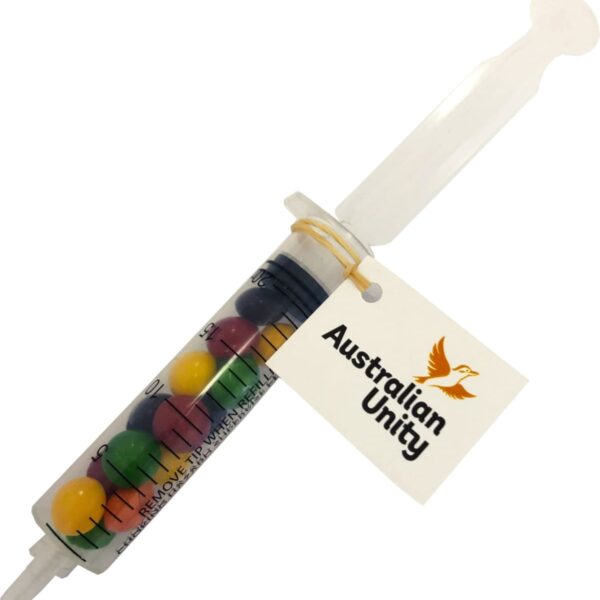 Plastic syringe filled with colorful candy, labeled Australian Unity on a tag.