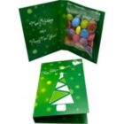 Green holiday card with tree design, open to reveal candies and festive message inside.