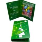 Green holiday card with tree design, open to reveal colorful candies and holiday greeting inside.