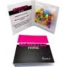 An open black and pink box displaying assorted colorful candy inside a clear pouch.