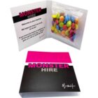 Greeting card labeled MONSTER HIRE with colorful candies in a small plastic bag inside.