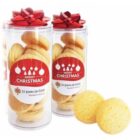 Two clear jars of cookies with red bows and Merry Christmas labels, plus two cookies in front.
