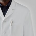 Person in a white lab coat with a pen in the pocket.