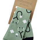 Green socks with stethoscope and medical cross design, attached to a cardboard packaging.