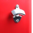Silver wall-mounted bottle opener on a bright red background.