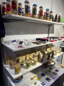 Shelves at APPA 2025 displaying jars, bags, and packets of cookies, snacks, and candies.