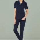 Person in navy scrubs and gray sneakers standing against a gray background.